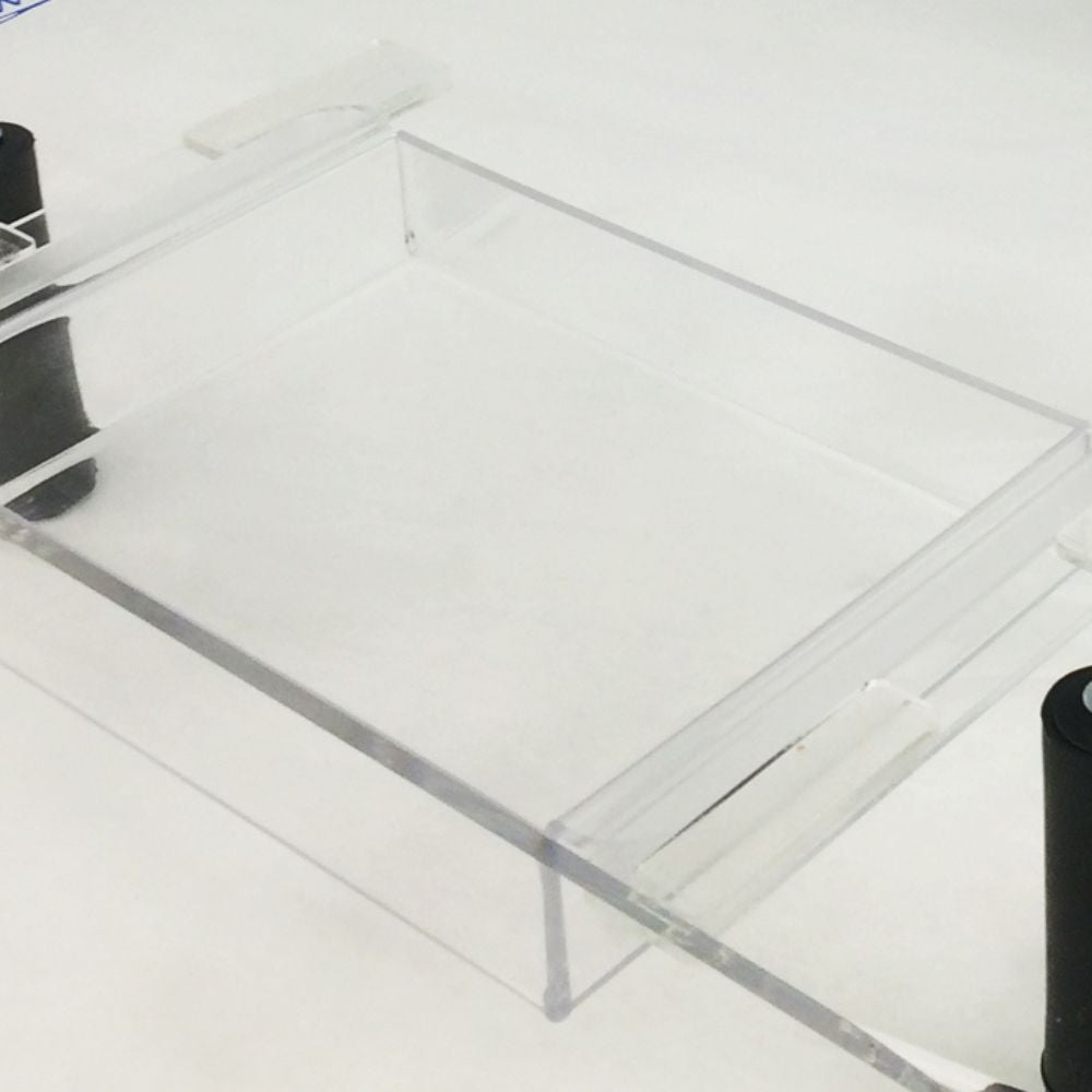 Clear acrylic drawer organizer tray on a white surface, showing transparent edges and a rectangular box design.