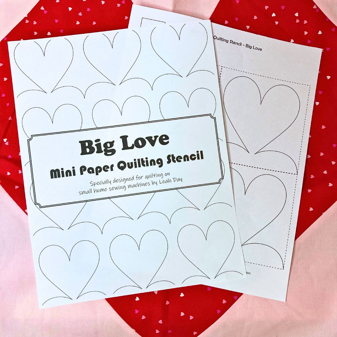 Two mini paper quilting stencils with heart designs on a red and pink heart background.
