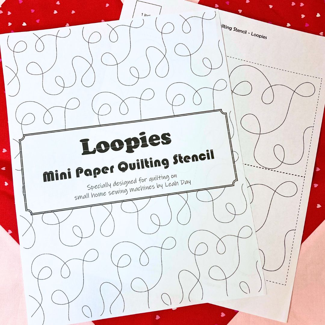 Loopies mini paper quilting stencil on a red and pink quilt background