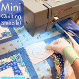 Sewing machine with a quilt and a hand holding a mini quilting stencil.