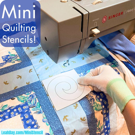 Sewing machine with a quilt and a hand holding a mini quilting stencil.