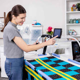 Smiling female using QuiltMotion X system on  Cutie Quilt Frame
