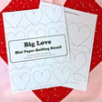 Two mini paper quilting stencils with heart designs on a red and pink heart background.
