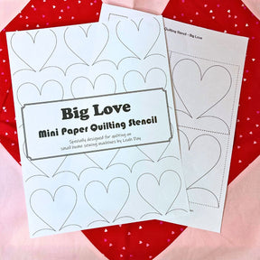 Two mini paper quilting stencils with heart designs on a red and pink heart background.