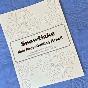 Snowflake mini paper quilting stencil on a blue quilted snowflake background