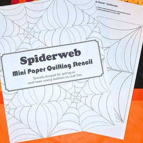 Spiderweb mini paper quilting stencil on an orange background
